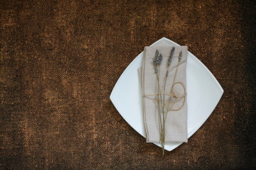 Linen beige napkin with lavender flower on the white plate