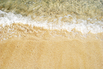 Sea water waves with bubbles on sand beach