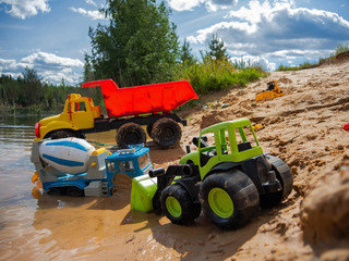 Children's toy cars on the sandy beach, in the water on a bright sunny summer day