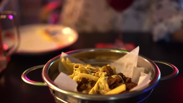 Eating cheesy fries in red neon night club