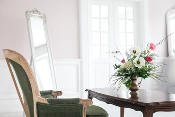 A bouquet of artificial flowers in a vase in the luxurious interior of the room. Soft focus.