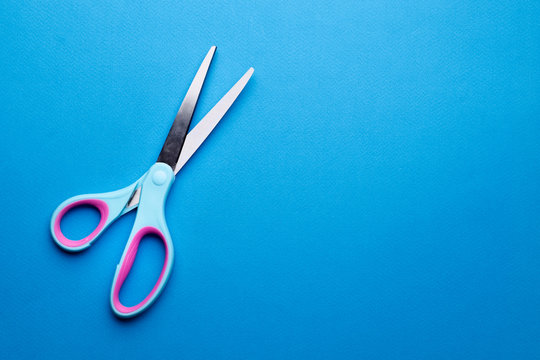 scissors on bright blue abstract blank paper background