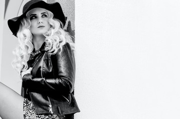 beautiful blonde girl in a brilliant dress and leather jacket. Black and white