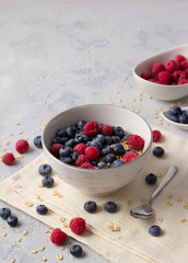 Oat flakes, blueberries and raspberries on grey concrete background.