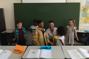 Front view of male firefighter teaching schoolkids about fire safety in classroom