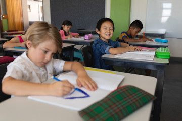Schoolboy looking at camera while studying in classroom