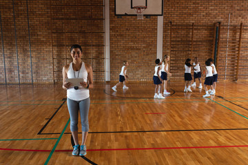 Smiling female basketball coach with digital tablet looking at camera