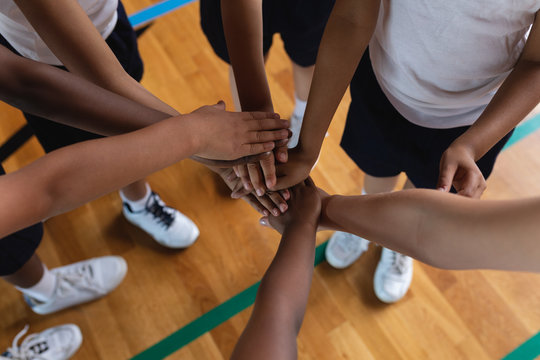Schoolkids forming hand stack at basketball court