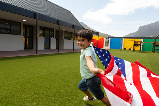 Schoolboy running with an American flag in the school playground - Powered by Adobe