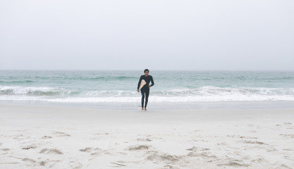 Male surfer running on the beach with surfboard