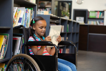Disabled schoolgirl using digital tablet in the library