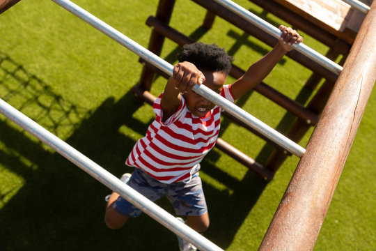 Schoolboy playing on horizontal ladder in the school playground