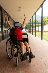 Obraz premium Happy disabled schoolboy using virtual reality headset in corridor