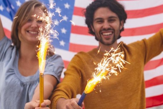 Caucasian couple playing with fire cracker while holding american flag