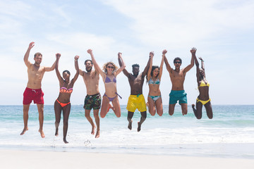 Obraz premium Group of friends enjoying and jumping in water at beach