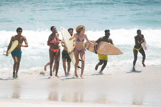 Group of friends holding surfboard at beach on a sunny day