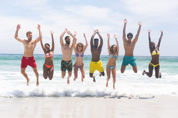 Group of friends relaxing and jumping in water at beach