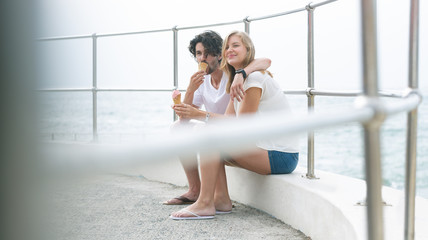 Caucasian couple siting at promenade while having ice cream cone 