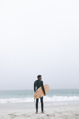 Male surfer holding surfboard on the beach