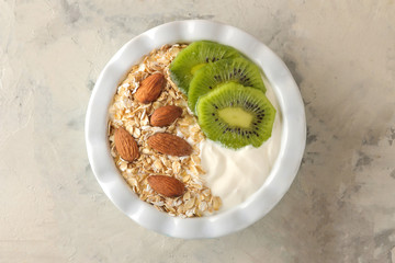 Greek white yoghurt with kiwi almonds and oatmeal on a light concrete table. breakfast. top view. healthy food