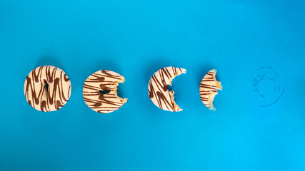 Eaten donut  with white chocolate and dark stripe on blue background. Top view.