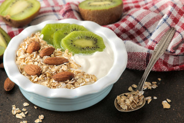 Greek white yogurt with kiwi almonds and oatmeal on a dark brown table. breakfast. healthy food