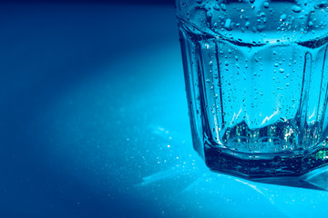 A glass with water drops  on a dark blue background close up