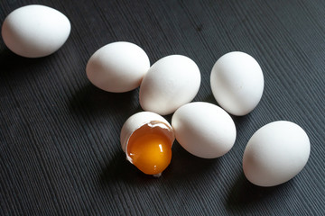 Half cracked egg on the black background. Egg yolk in the egg shell on the black background. Organic eggs.