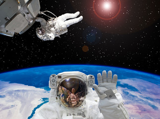Astronaut waving. Other astronaut on the backdrop. Space scene. The elements of this image...