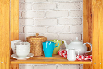 Kitchen utensils and dishware on wooden shelf