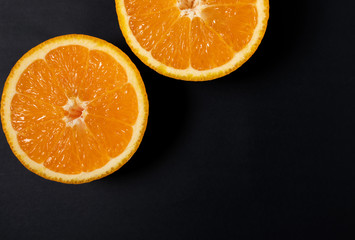 Orange slice on black background, top view