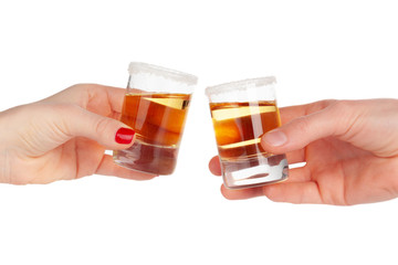Two hands clinking shots of alcoholic beverage together