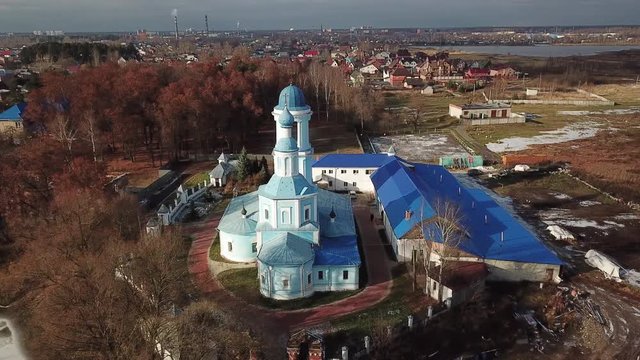 Beautiful orthodox church on the bank of the river Klyazma in the city of Noginsk. The picturesque surroundings with a dam on the river. Sunny autumn day.