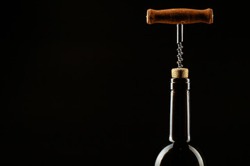 Corkscrew screwed into the cork in the bottle of wine