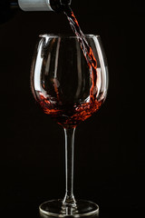 Red wine being poured in a wine glass on a dark background