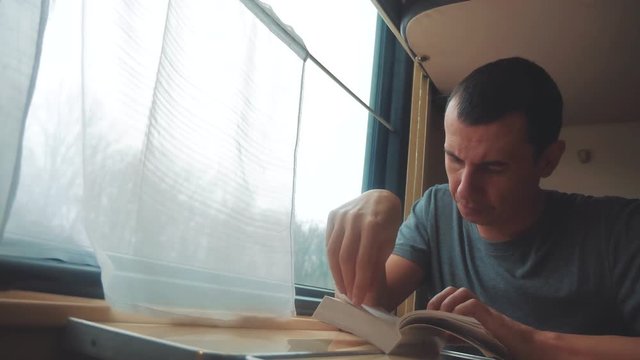 man reading a book in a train long journey. railroad travel concept coach train journey lifestyle . view beautiful from the window of a moving train railway Russia winter. interior inside train
