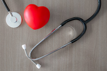 stethoscope and glow red heart on wooden table.