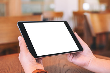 Mockup image of hands sitting and holding black tablet pc with blank white desktop screen