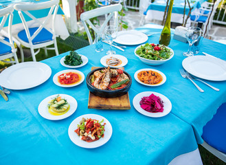 Fototapeta premium Shrimp, Seafoods, appetizers and salads on the table in Fish Restaurant. Beach Restaurant in Greece or Turkey. Aegean seaside, Greek or Turkish style fish restaurant in Bodrum, Santorini or Mykonos