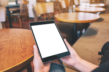 Mockup image of woman sitting and holding black tablet pc with blank white desktop screen
