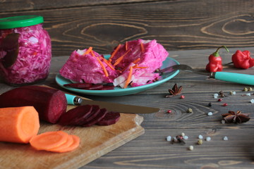 Sauerkraut with beetroot, on a platter and bank on a wooden background.