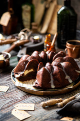 Delicious homemade chocolate bundt cake on wooden plate stands on rustic table
