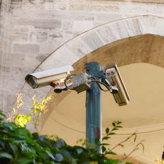 security cameras pointing in different directions on the pole, cityscape, color