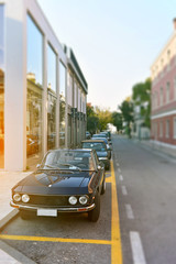 street with parked old cars in perspective, blurred background, cityscape