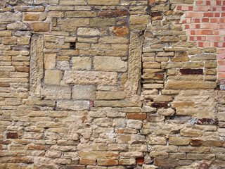 an old much repaired and patched wall mad of mixed types of bricks and stones
