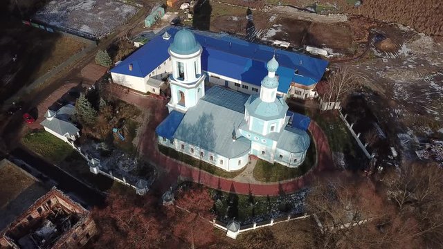Beautiful orthodox church on the bank of the river Klyazma in the city of Noginsk. The picturesque surroundings with a dam on the river. Sunny autumn day.