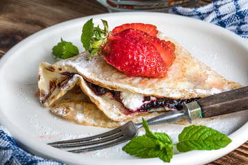 Polish pancakes with jam, cheese and strawberries.