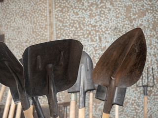 Metal shovels with wooden handles. Concept of garden tools. Background concrete wall.