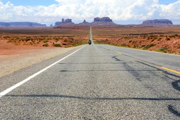 Foto op Plexiglas motorfiets nadert op rechte weg in Monument Valley © mikesch112