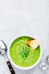 Asparagus cream soup with croutons on gray stone background.